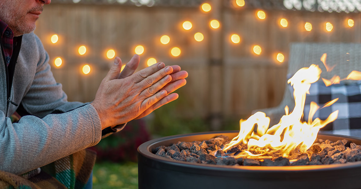 Man warming hands next to a fire.